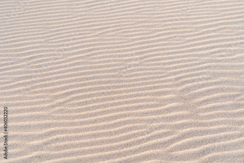 White sand texture waves close up. Wavy background pattern of sandy beach. 
