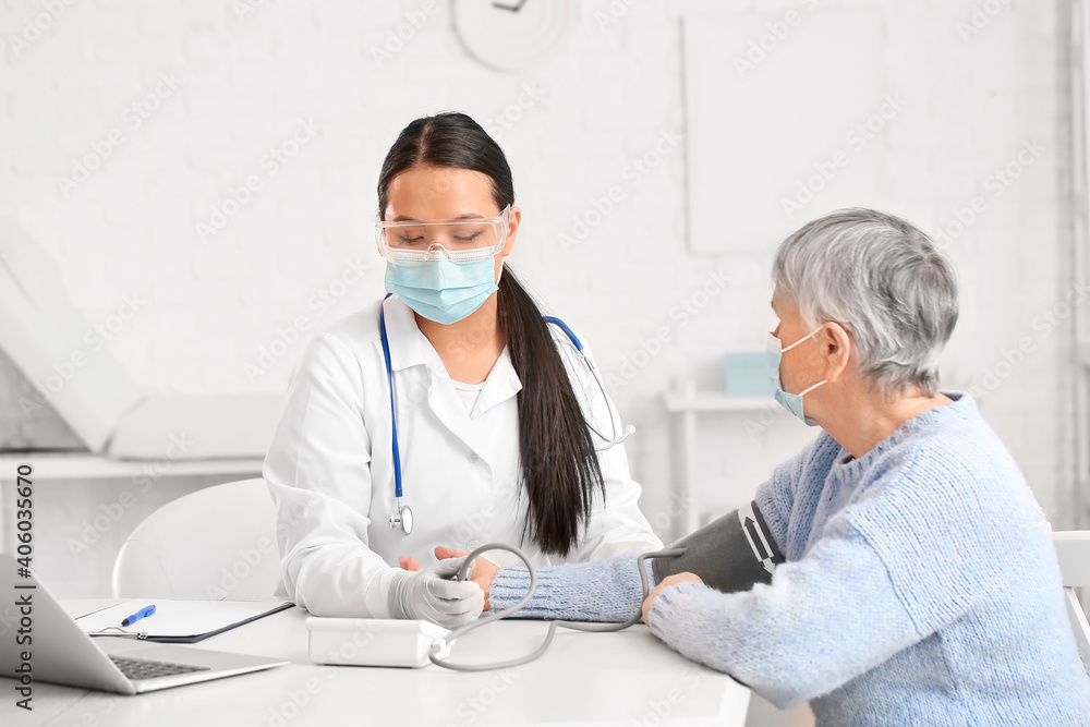 Doctor measuring blood pressure of senior woman in clinic Doctor measuring blood pressure of senior woman in clinic
