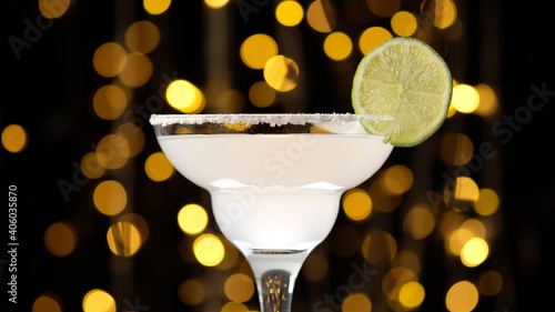 Margarita cocktail from tequila and lemon over Bokeh Blinking background. Glass with a cocktail. Party, Success, holiday celebrating