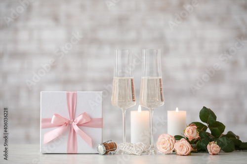 Glasses of champagne  flowers  candles and gift for Valentine s Day on table