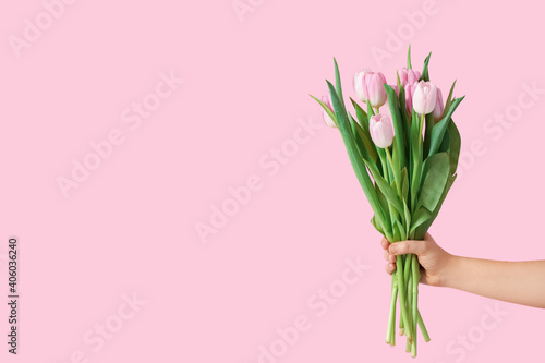 Hand with bouquet of beautiful tulips on color background © Pixel-Shot