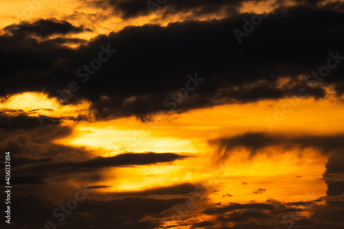 Golden sunset sky with dark clouds. Beauty in nature. Beautiful sunset sky abstract background. Orange and yellow sky with black clouds at dusk. Sky at dusk. Peaceful and tranquil concept. © Artinun