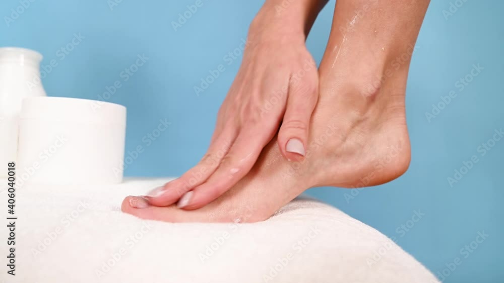 custom made wallpaper toronto digitalWoman applies lotion to her feet on white towel. Female beautiful feet, towel and cosmetic products on blue background, side view. Spa treatment