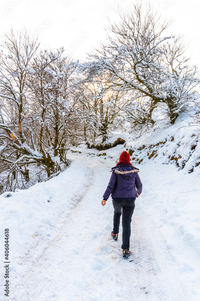 A young woman walking through the snow in the snow-covered Oianleku natural park in the town of Oiartzun, next to Peñas de Aya in winter, Gipuzkoa. Basque Country