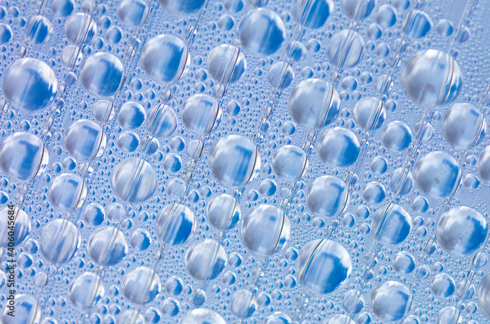 Water drops on blue glass as an abstract background.