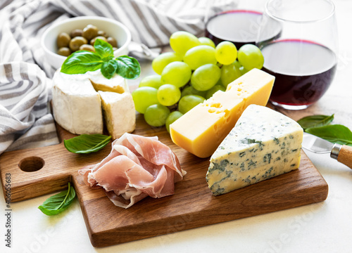 Various types of cheese, grapes, wine and snacks
