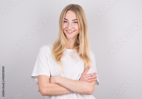 Happy cheerful young blond teenager with arms crossed looking at camera with joyful and charming smile.