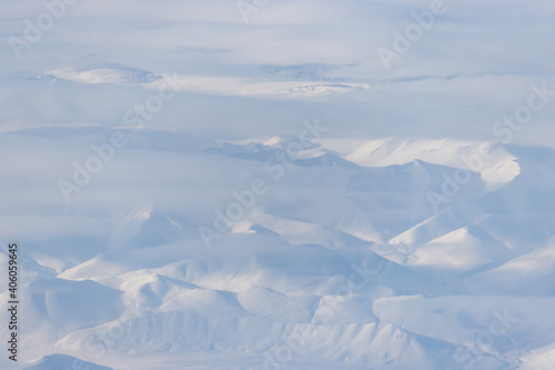 Aerial view of snow-capped mountains and clouds. Winter snowy mountain landscape. Kolyma Mountains on the border of Kamchatka Territory and Magadan Region, Siberia, Far East Russia. Great background.