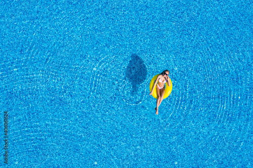 Aerial view of young woman swimming on the inflatable big yellow ring in pool