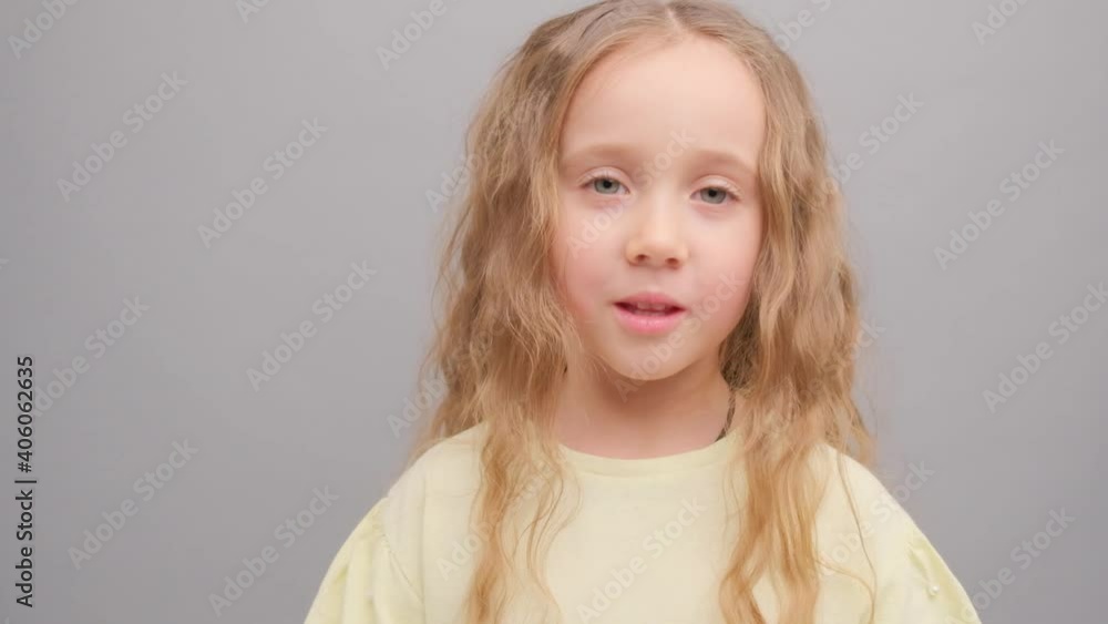 Little girl is surprised looking into the camera. Picture taken in the studio on a gray background. Super slow motion. Little girl is surprised looking into the camera. Picture taken in the studio on a gray background. Super slow motion.