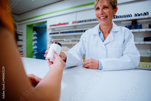 Senior Caucasian pharmacist providing medication to mixed race female patient 