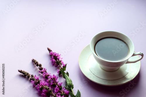 Bouquet of purple wildflowers with a cup of tea on a pastel background, side view, space for text