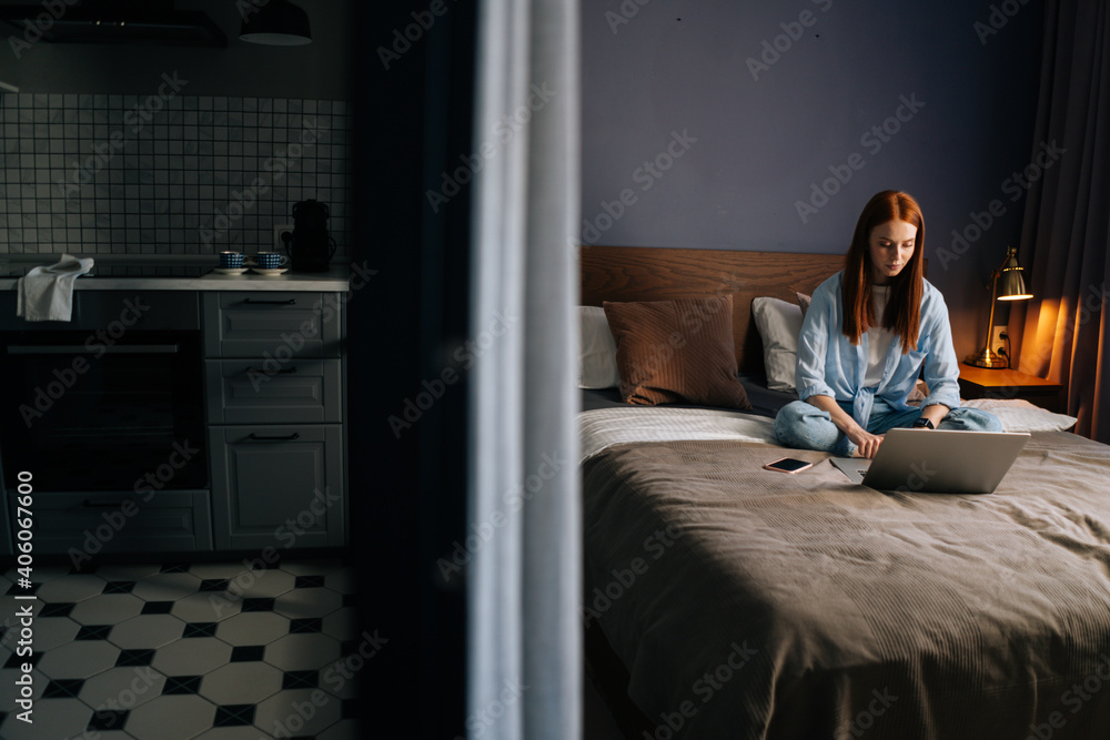 Attractive redhead young woman making video call on webcam sitting on bed at cute bedroom. Happy lady smiling in lotus pose using laptop computer. Pretty female having online video chat with friends Attractive redhead young woman making video call on webcam sitting on bed at cute bedroom. Happy lady smiling in lotus pose using laptop computer. Pretty female having online video chat with friends