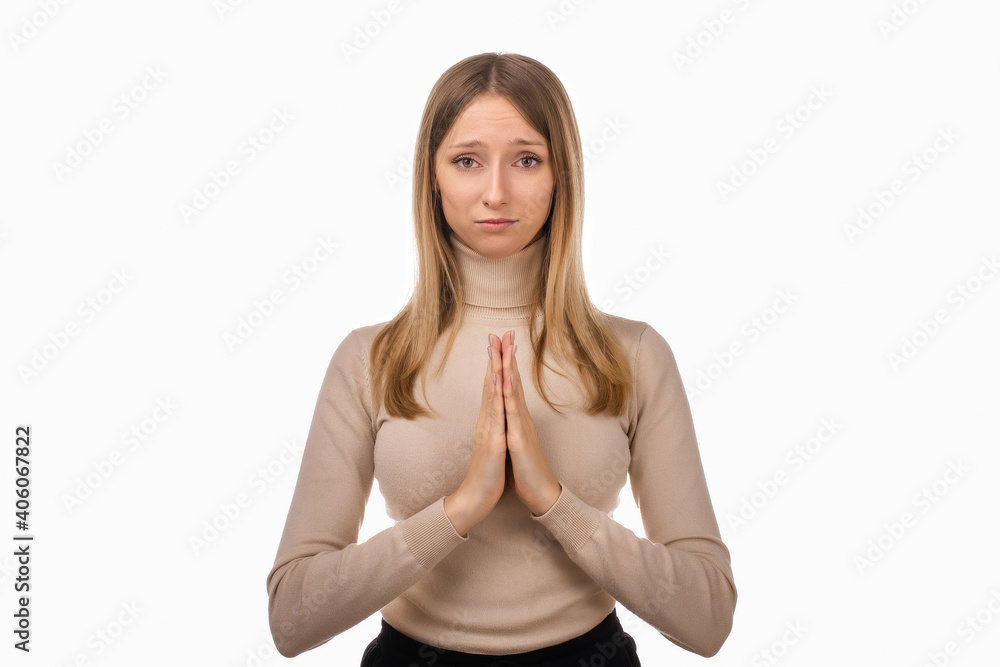 Attractive blond girl prays for wellness of family, keeps palms pressed together in praying gesture