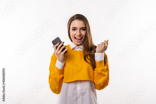 Smiling young brunette womanis using mobile phone, typing sms message. Technology, youth and communication concept