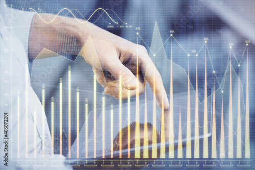 Double exposure of man's hands holding and using a digital device and forex graph drawing. Financial market concept. © peshkova