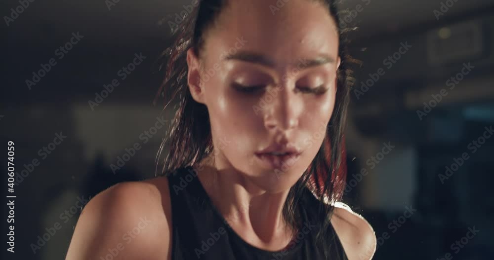 Portrait of athletic girl running fast on a treadmill in a dark backlit gym Portrait of athletic girl running fast on a treadmill in a dark backlit gym