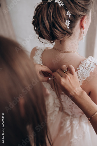 the bride's friend adjusts her wedding dress