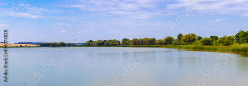 Spacious lake and a narrow strip of land between the water and the sky, panorama