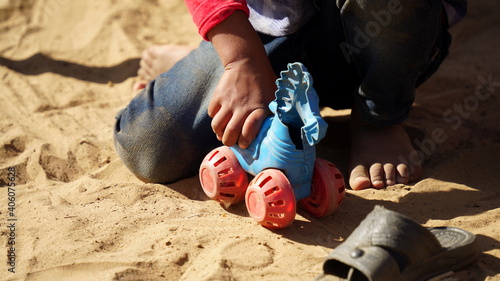 Picture shot of Indian kid holding blue toy in hand walking it soil ground. photo