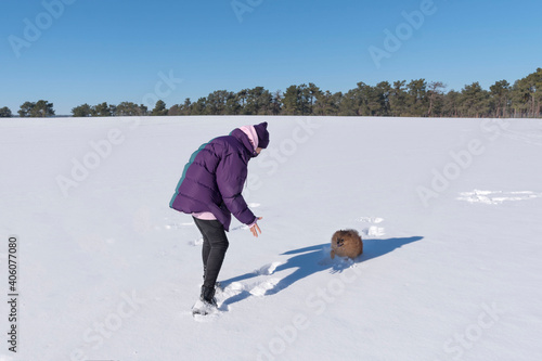 Shallow focus shot of a young female playing with her Pomeranian dog on a snow