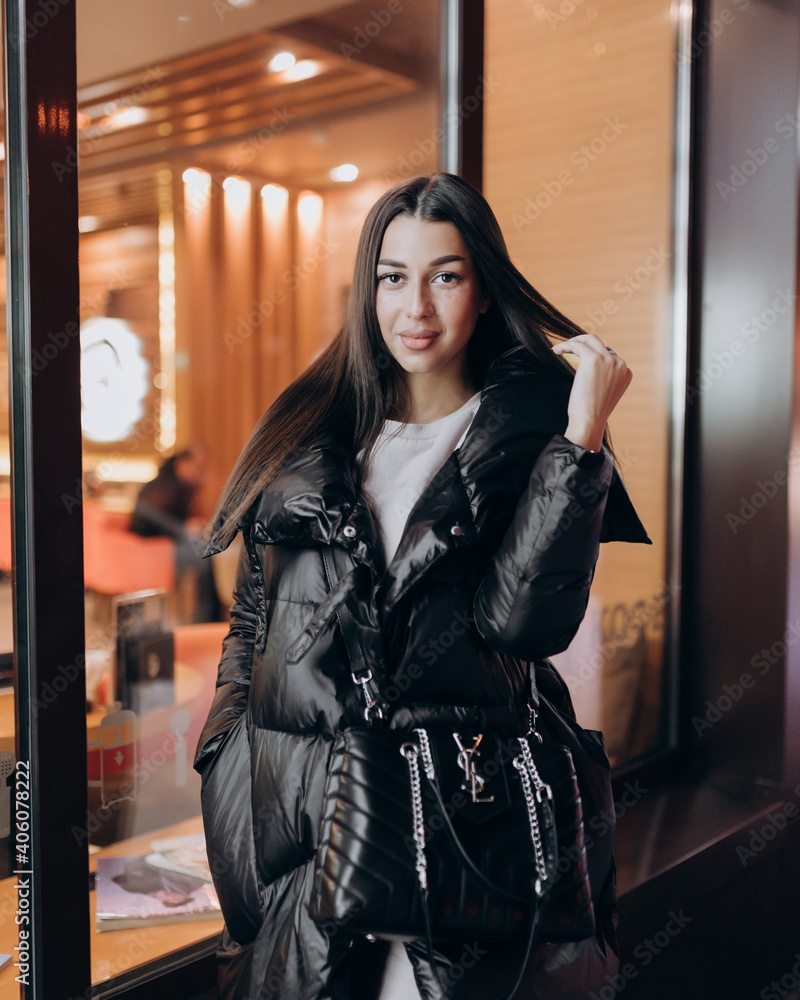 beautiful girl with long dark hair in a black jacket in the winter night on the street