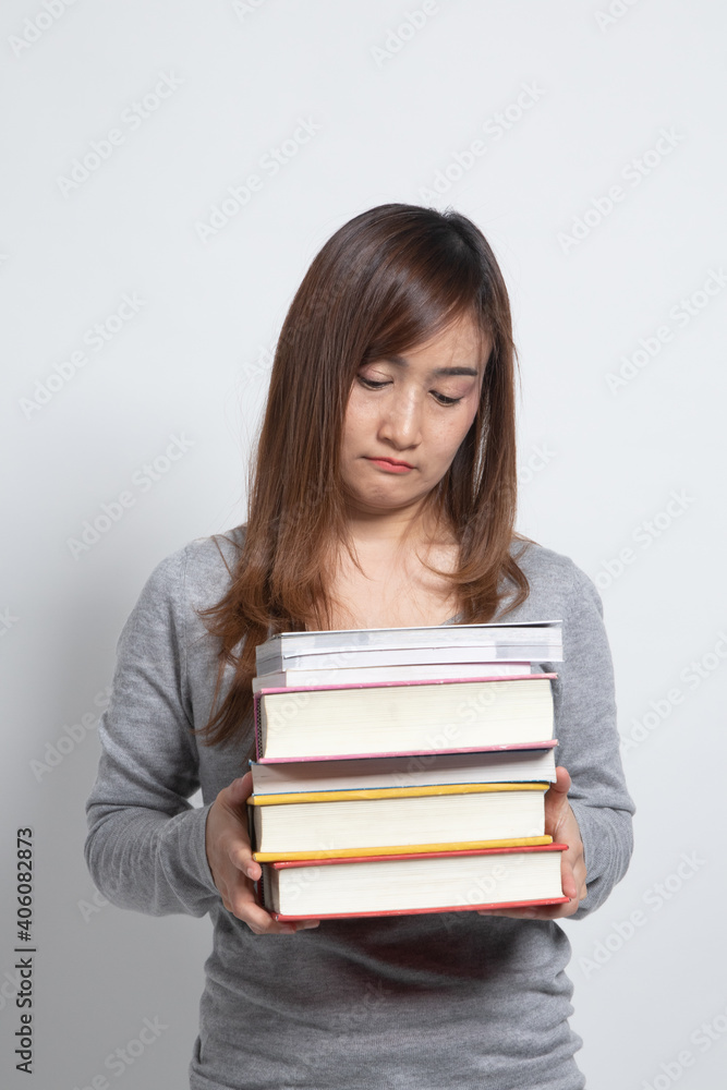 Unhappy young Asian woman studying with may books. Unhappy young Asian woman studying with may books.