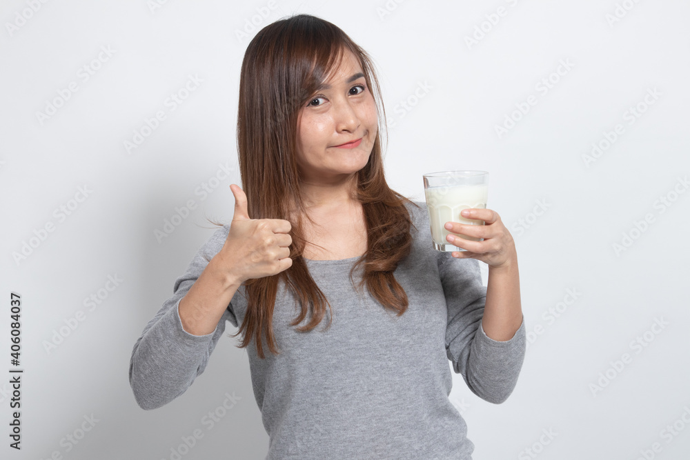Healthy Asian woman drinking a glass of milk thumbs up.