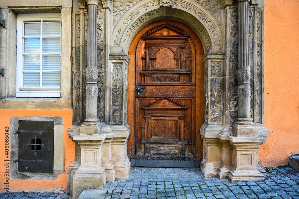 A house entrance with an antique wooden door with beautiful carvings and a metal door handle.