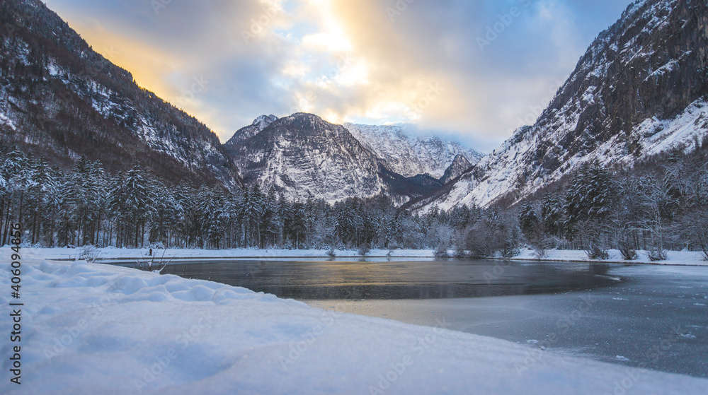 Winter landscape with frosty lake, snowy trees and mountains. Buntautal and Bluntausee.