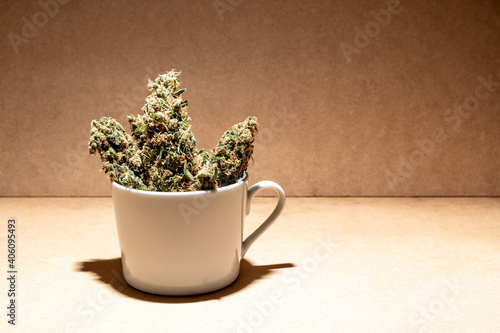 Ready to consume medical marihuana buds inside a coffee cup. Selective focus on brown background.
