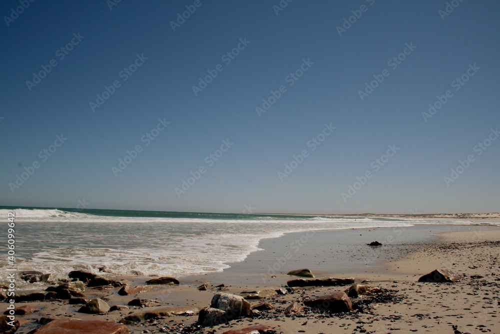 Moody ocean on a sunny day. Rocks and sand on the beach