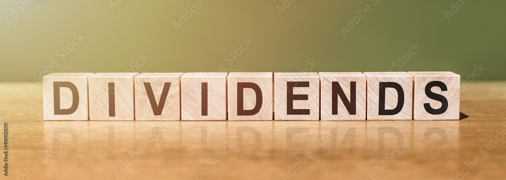 DIVIDENDS word written on wooden blocks on wooden table. Concept for your design. DIVIDENDS word written on wooden blocks on wooden table. Concept for your design.