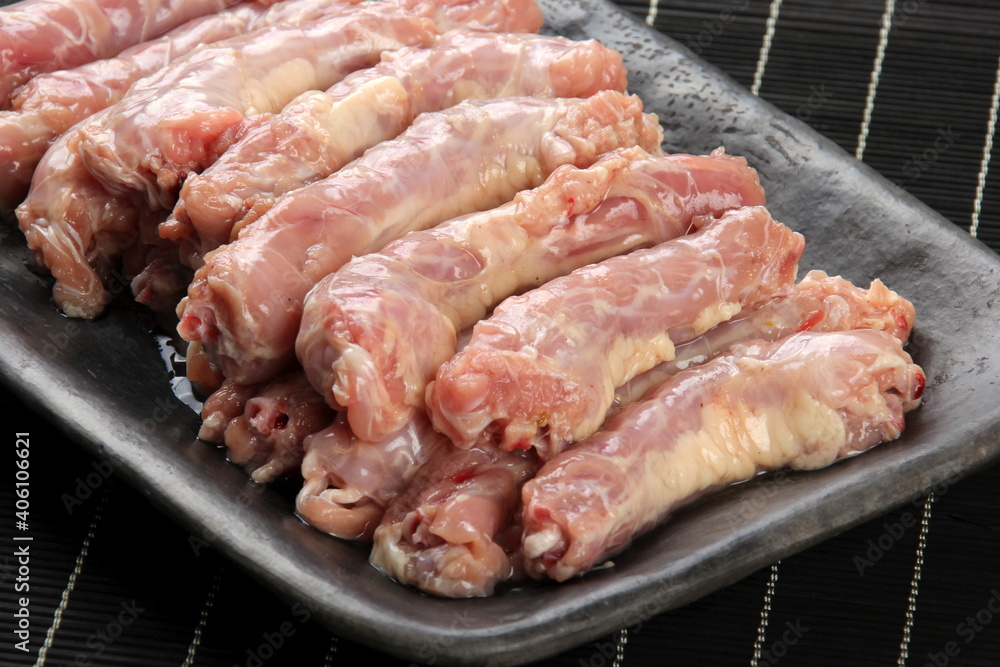 Raw Chicken neck skinless on a clay plate, Black bamboo napkin in the background Raw Chicken neck skinless on a clay plate, Black bamboo napkin in the background