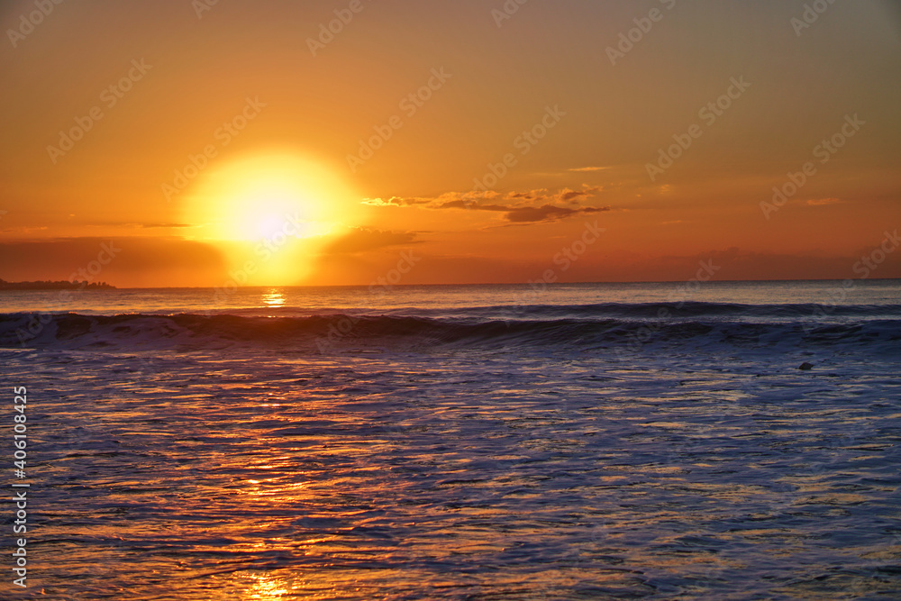 The sun rises over the horizon at the dawn of the sea. Ocean at sunset. Sandy blyaz and a wave on the seashore. High quality photo