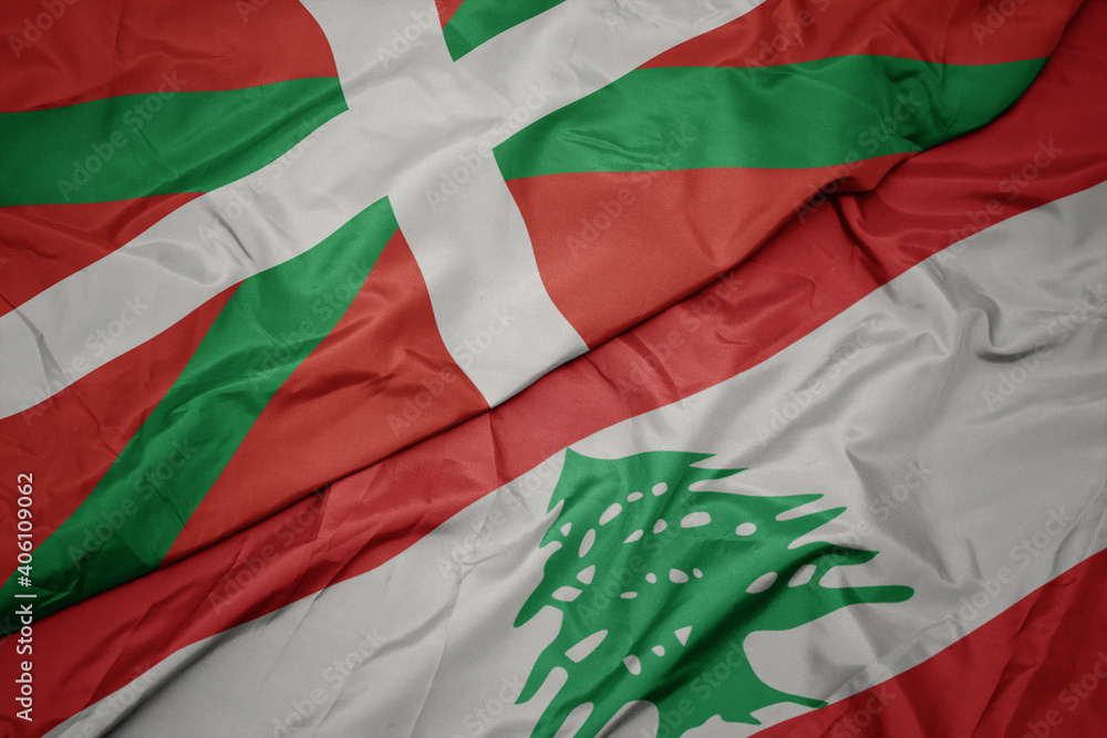 waving colorful flag of lebanon and national flag of basque country.
