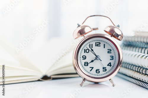 Bell alarm clock with blurred books for time management for study and work concept