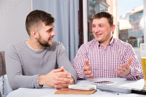 Two cheerful men enjoying conversation at home table