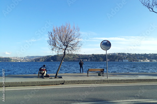 People fishing in the Bosphorus and people walking on the beach enjoy the sunny weather in Emirgan, Istanbul, Turkey, 10 January 2021