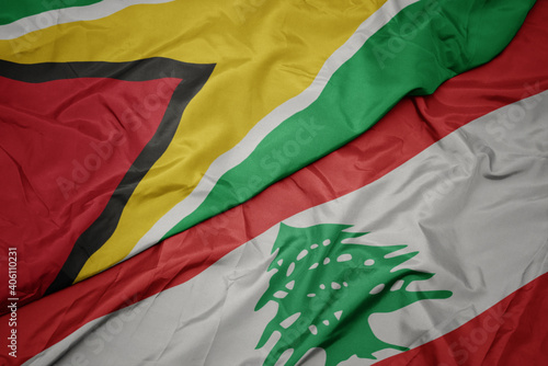 waving colorful flag of lebanon and national flag of guyana. photo