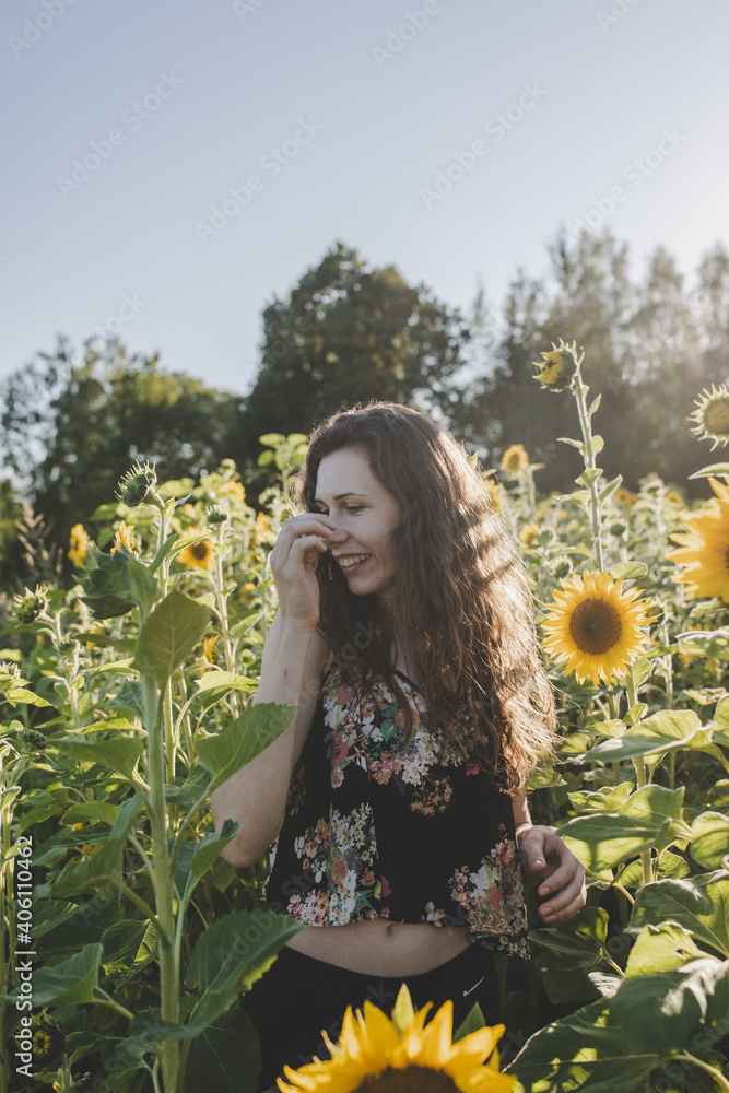 Young attractive caucasian white woman with brown curly hair laughing from joy in yellow, sunflower field on sunny summer day. Joy, happiness, freedom context. Young attractive caucasian white woman with brown curly hair laughing from joy in yellow, sunflower field on sunny summer day. Joy, happiness, freedom context.