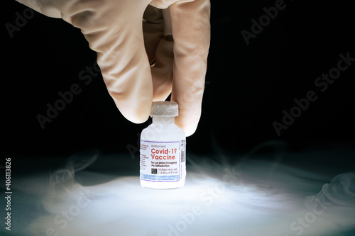 Researcher's hand pick up frozen cold Vaccine vial for Covid-19 with mRNA technology stored in subzero low temperature -70 celsius. Effective thermal controlled for global distribution conditions. photo