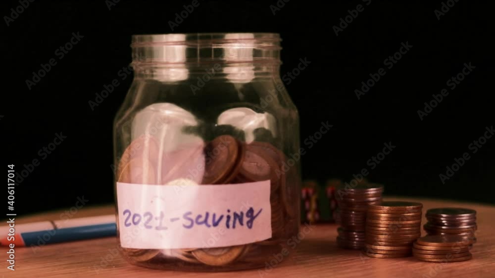 Coins in glass jar for money saving financial concept,man holding coins putting in glass,coin for saving,money 2021 saving concept,rotation saving jar on wooden table with black background
