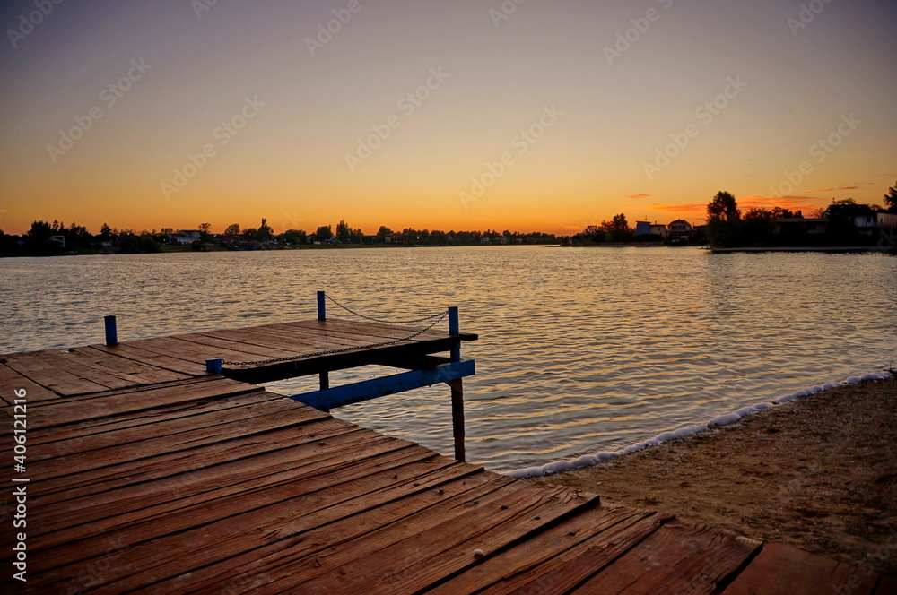 Lake Slnecne jazera in Senec at sunrise, with a pier in the foreground and line of trees on the horizon - Slovakia, Europe