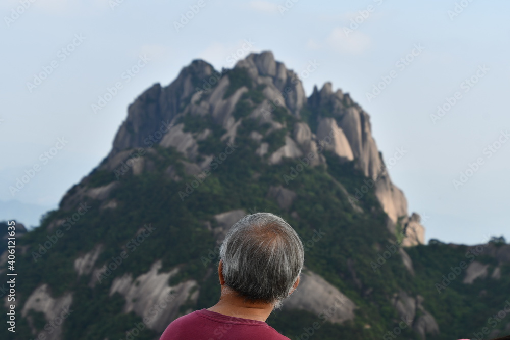 Old chinese man from the back is ovserving monumental pick of Huangshan, China Old chinese man from the back is ovserving monumental pick of Huangshan, China