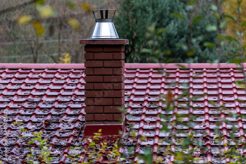 brick chimney on the red roof after the rain in autumn