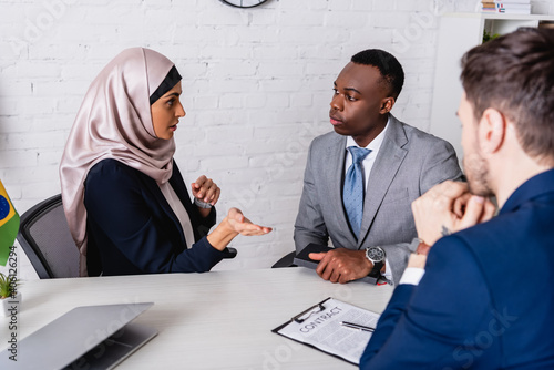 Tableau sur toile arabian businesswoman pointing with hand during meeting with multicultural busin