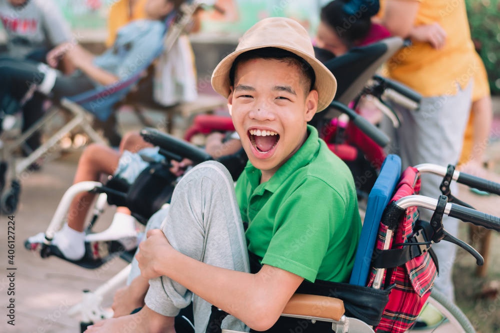 Naklejka premium Asian disabled child on wheelchair is playing, learning and exercise in the outdoor park with friends and teacher, Lifestyle of children in the special education school, Happy disability kid concept.