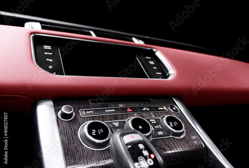 Red luxury modern car Interior. Steering wheel, shift lever and dashboard. Detail of modern car interior. Automatic gear stick. Part of leather seats with stitching in expensive car © Aleksei