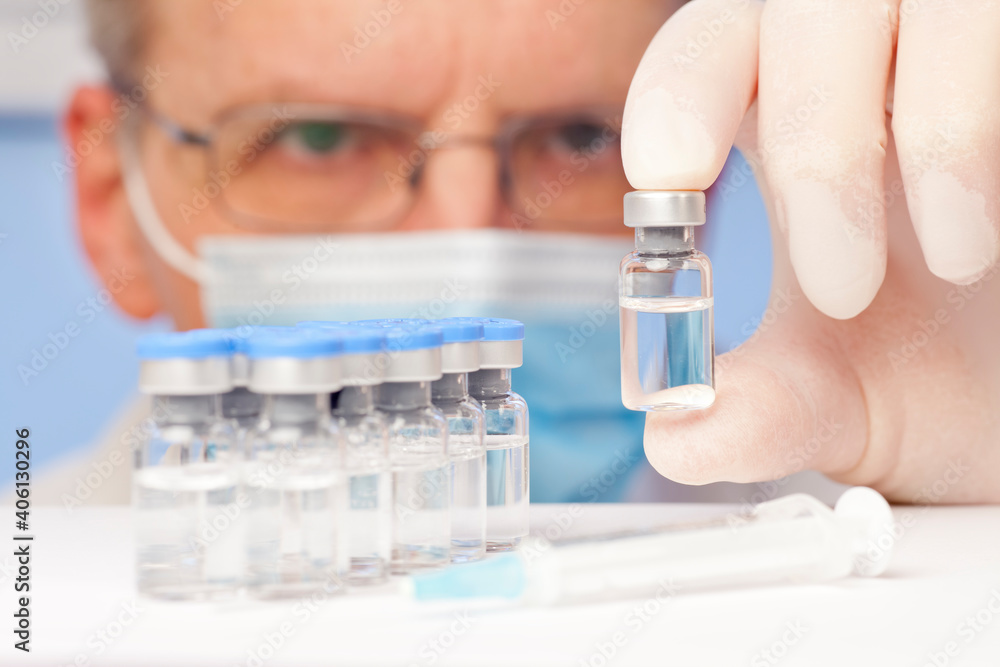 Doctor or scientist holding a vial with vaccine against covid-19 or influenza in his hand Doctor or scientist holding a vial with vaccine against covid-19 or influenza in his hand